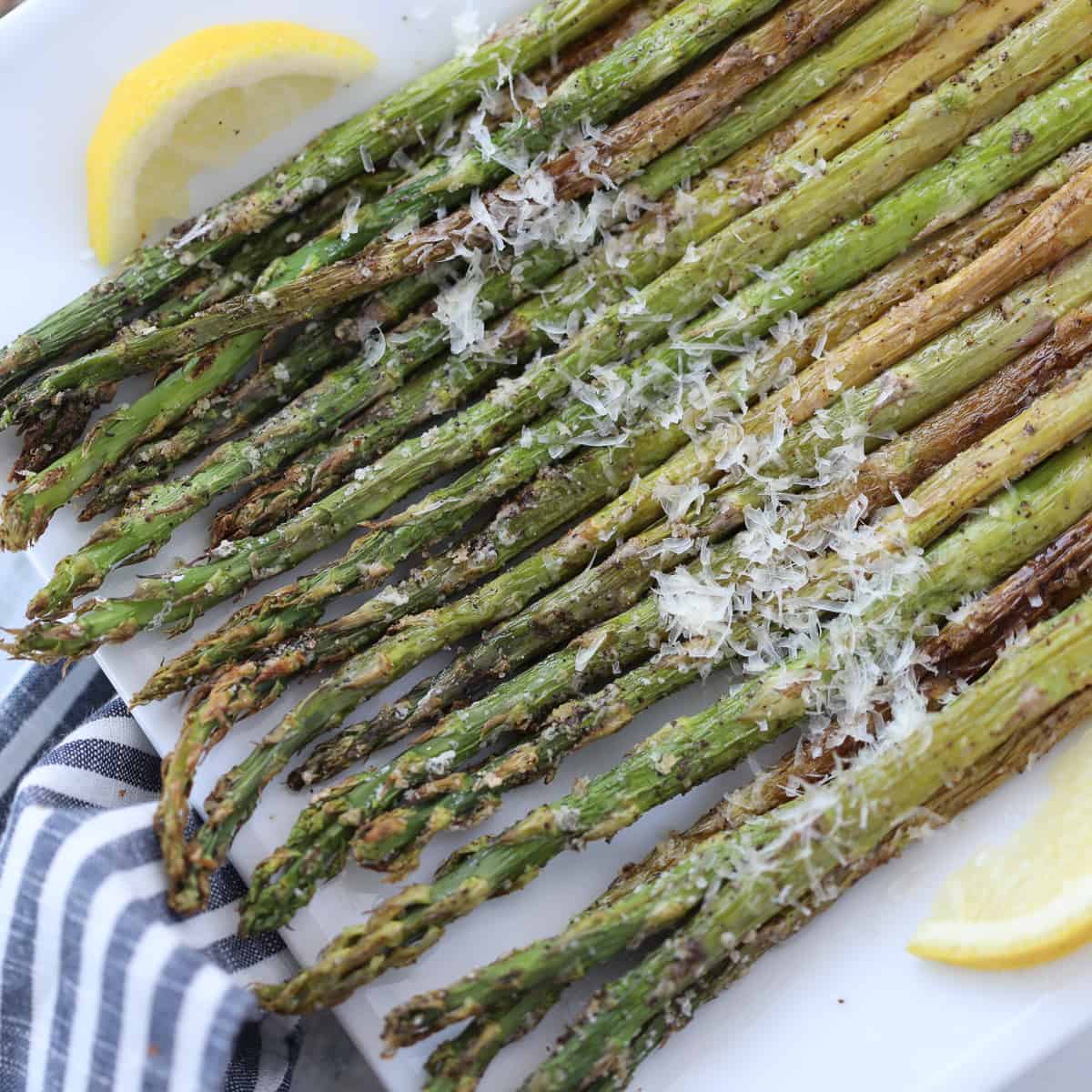 asparagus in air fryer topped with parmesan on a white plate