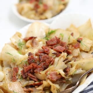 crockpot cabbage in a white serving dish garnished with bacon