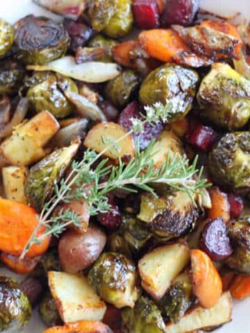 fall roasted vegetable in a white bowl topped with rosemary
