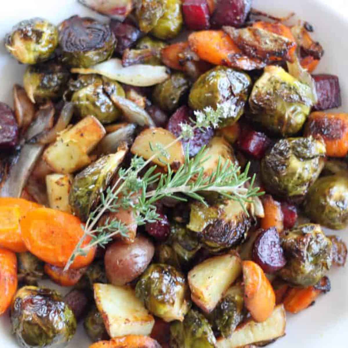 fall roasted vegetable in a white bowl topped with rosemary