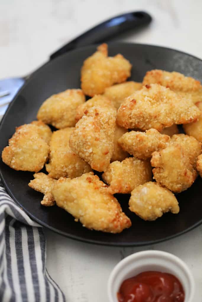 frozen chicken nuggets in air fryer recipe on a black plate with sauce