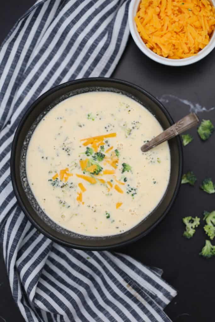 keto broccoli cheese soup with garnishes in a black bowl