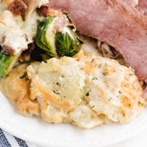 instant pot au gratin potatoes on a plate with ham and brussels sprouts