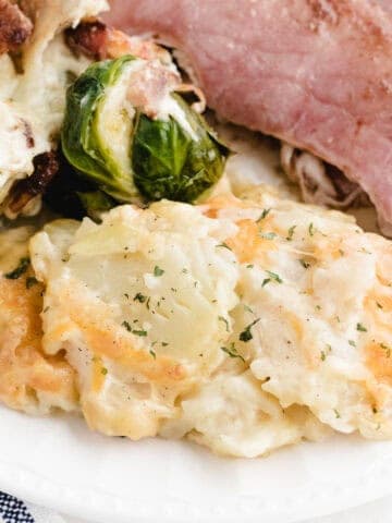 instant pot au gratin potatoes on a plate with ham and brussels sprouts