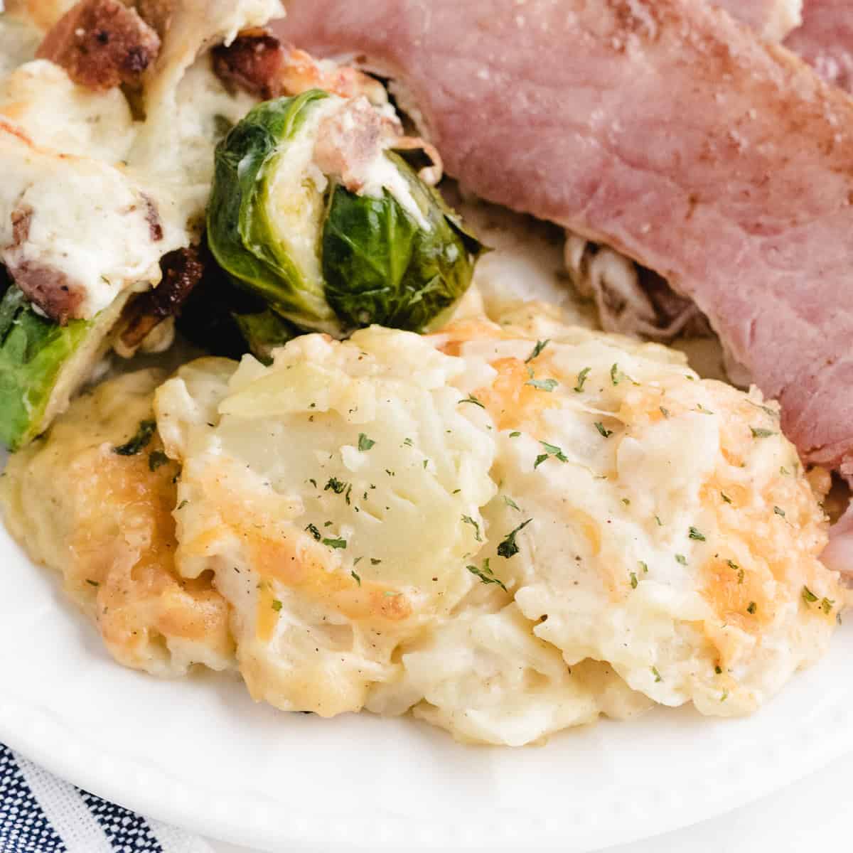 instant pot au gratin potatoes on a plate with ham and brussels sprouts