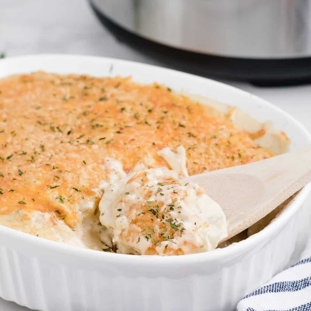 scooping scalloped potatoes with a wooden spoon after cooking