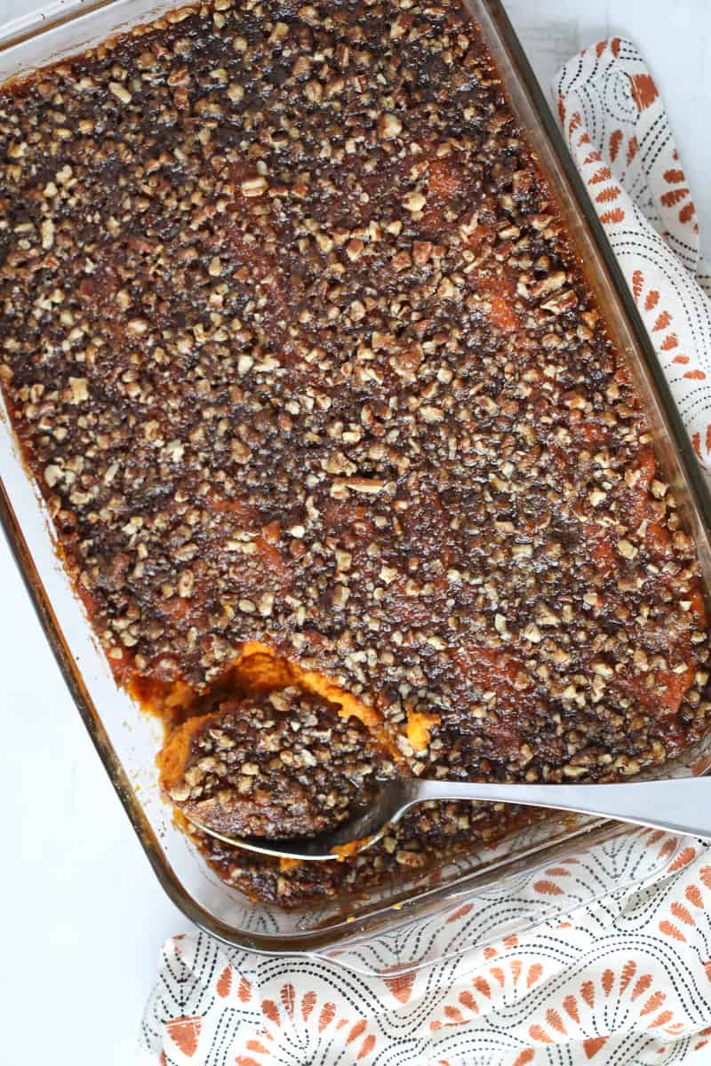 mashed sweet potatoes with pecans and maple syrup in a pyrex 9x13 pan