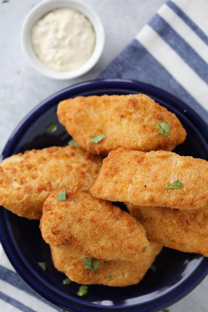 air fryer frozen fish on a blue plate with sauce