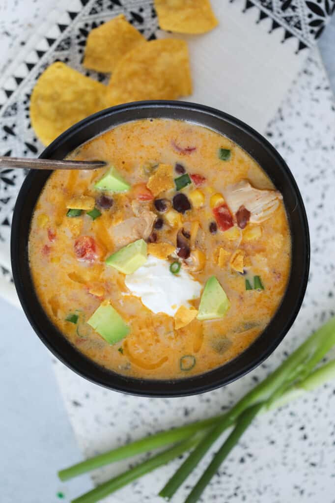 chicken taco soup instant pot recipe in a black bowl with garnishes
