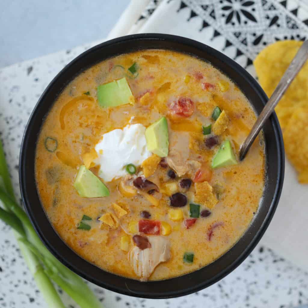 instant pot chicken taco soup with sour cream and cheddar cheese on a white background