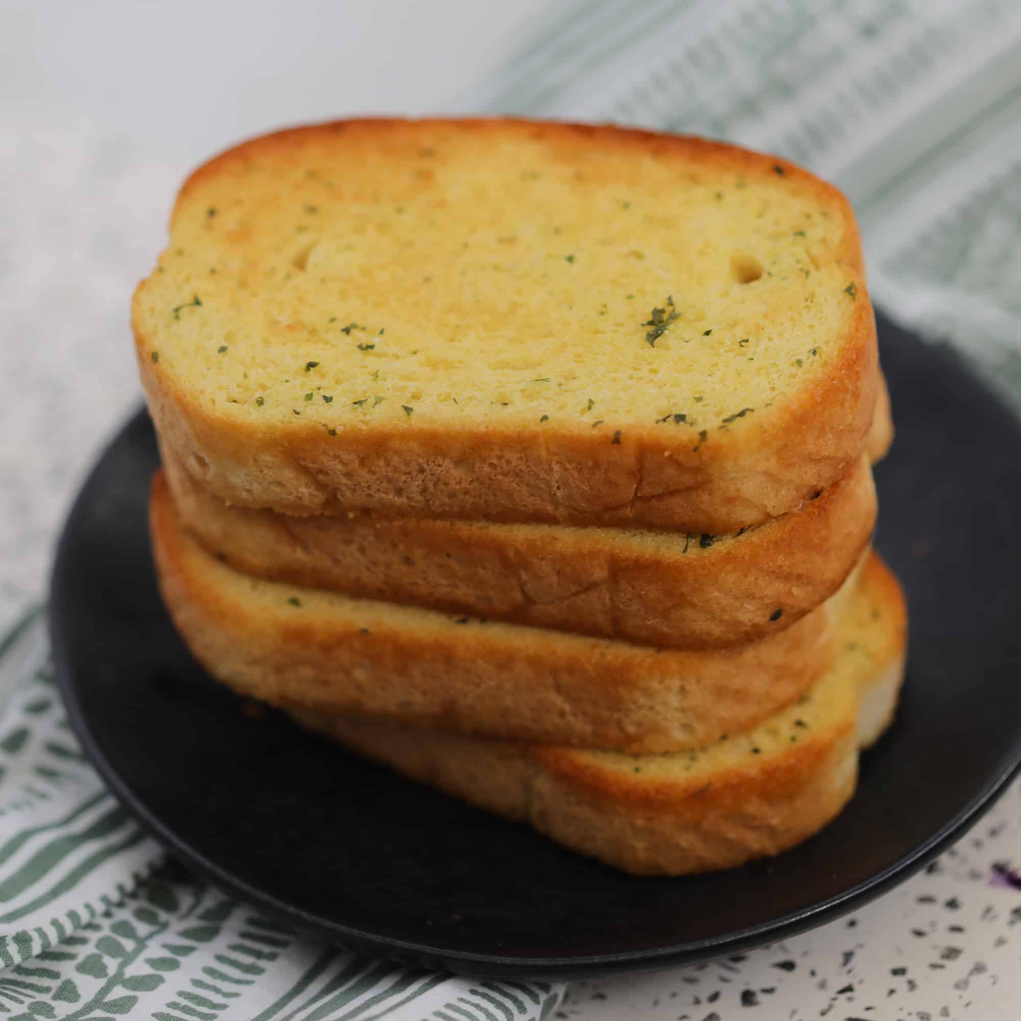 air fryer frozen garlic bread stacked on a black plate