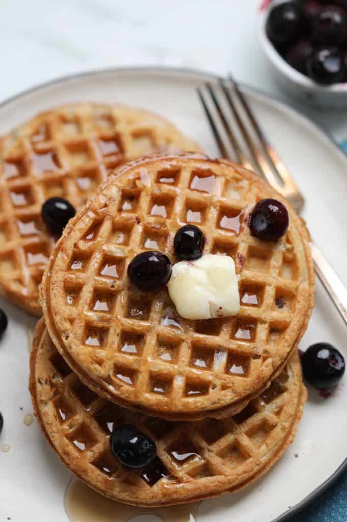 air fryer frozen waffles on a white plate with butter and blueberries