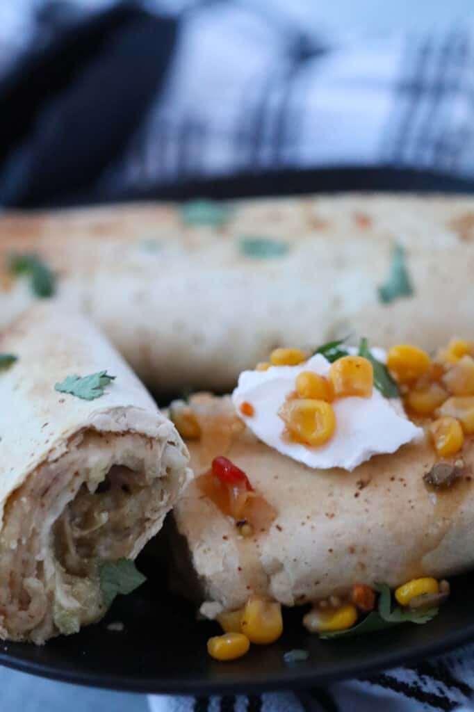 the frozen burrito in air fryer after cooking broken in half on a black plate