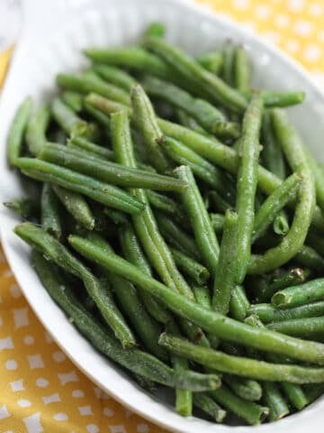 frozen green beans in air fryer ready to serve in a white dish that are healthy