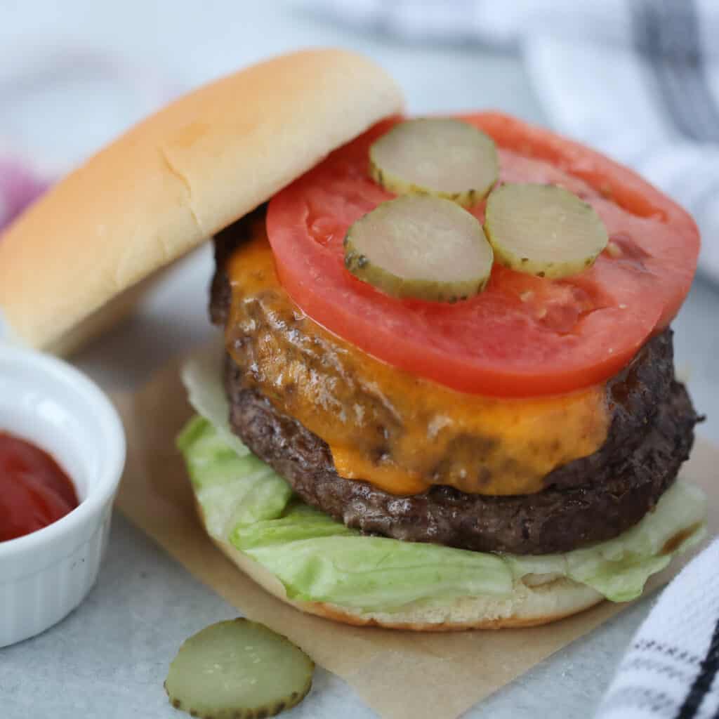 frozen hamburgers in air fryer with the bun leaning against the cooked burger
