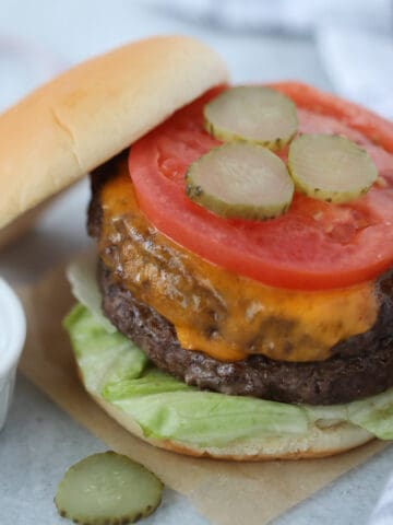 frozen hamburgers in air fryer with the bun leaning against the cooked burger