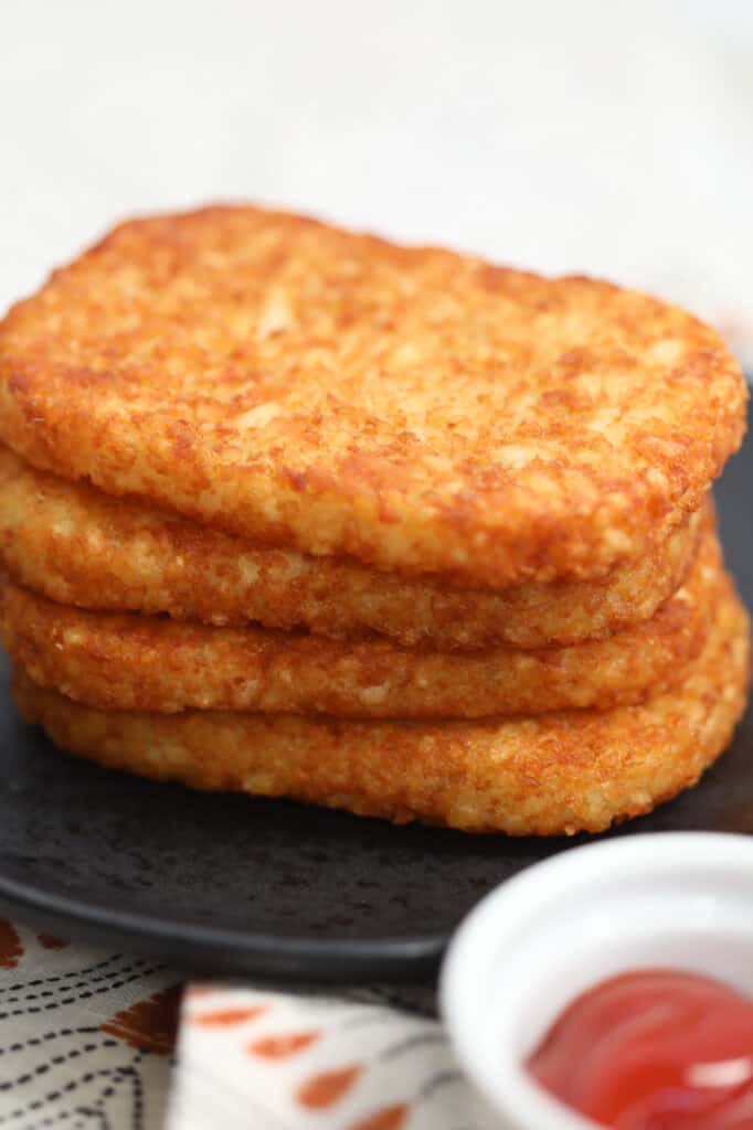 frozen hash browns in air fryer stacked on a black plate