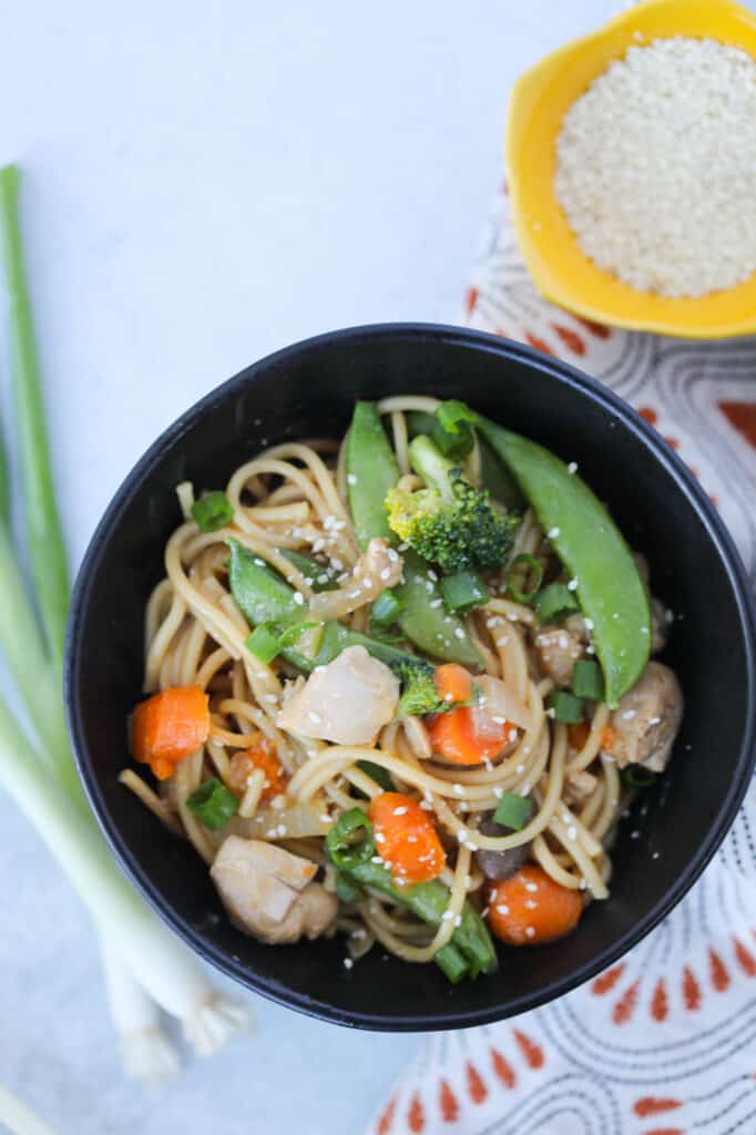 instant pot chicken lo mein in a black bowl with garnishes