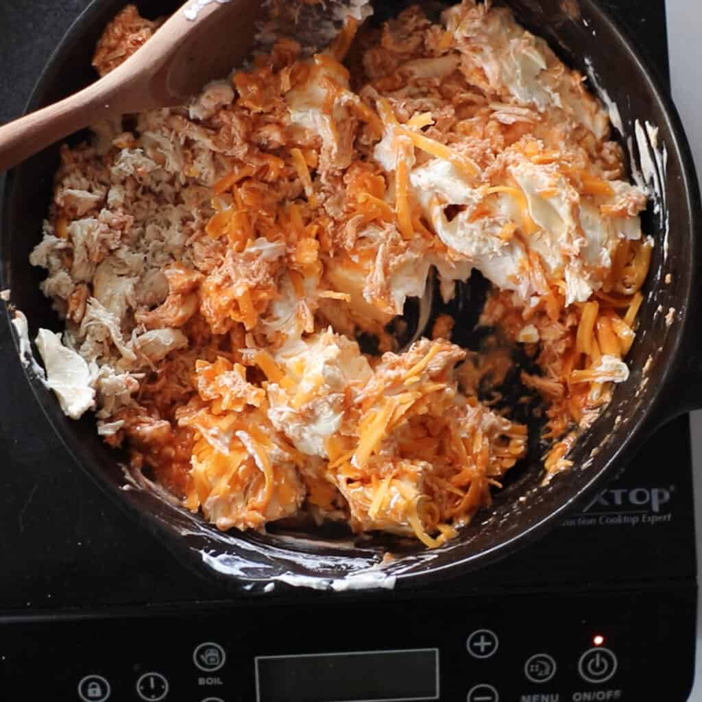 keto buffalo chicken dip ingredients getting added to a pan