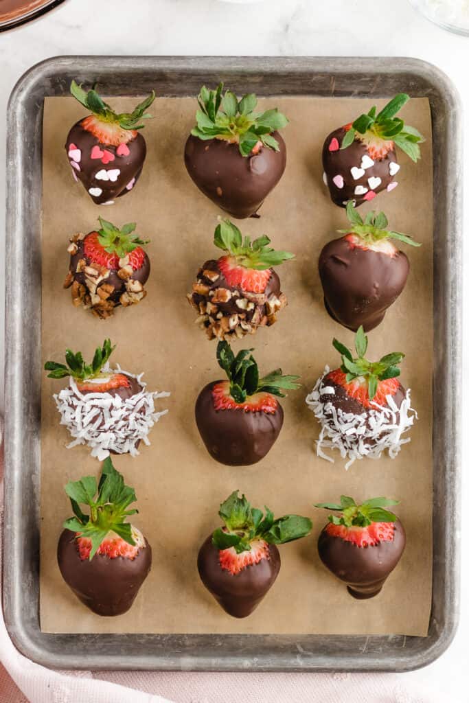 chocolate covered strawberries getting placed on parchment after getting dipped in chocolate