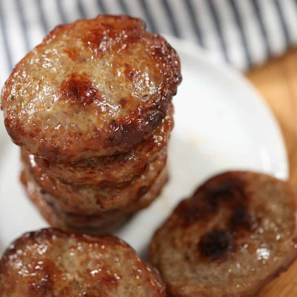 air fryer sausage patties on a white dish after cooking