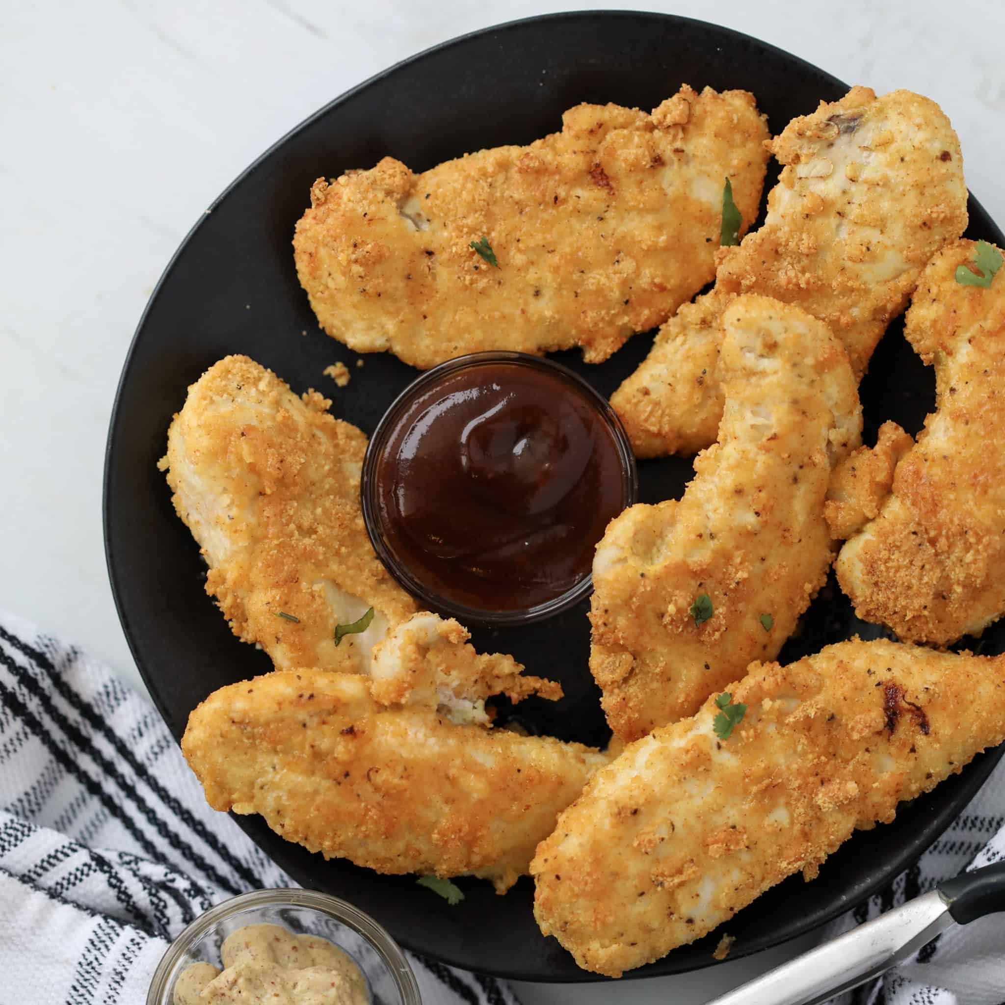 keto air fryer chicken tenders with almond flour and parmesan on a black plate