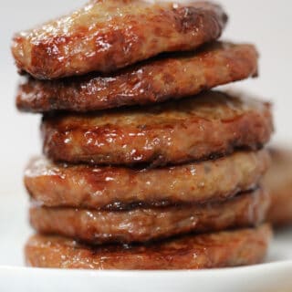 sausage patties in air fryer stacked on a white plate