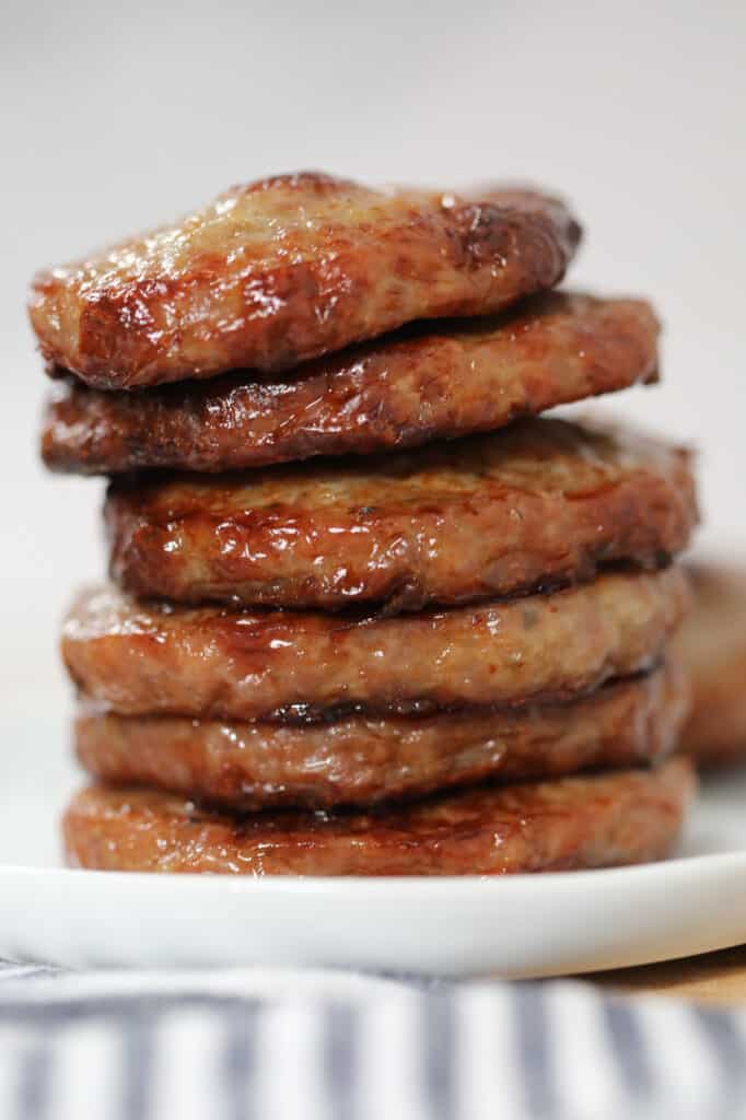 sausage patties in air fryer stacked on a white plate