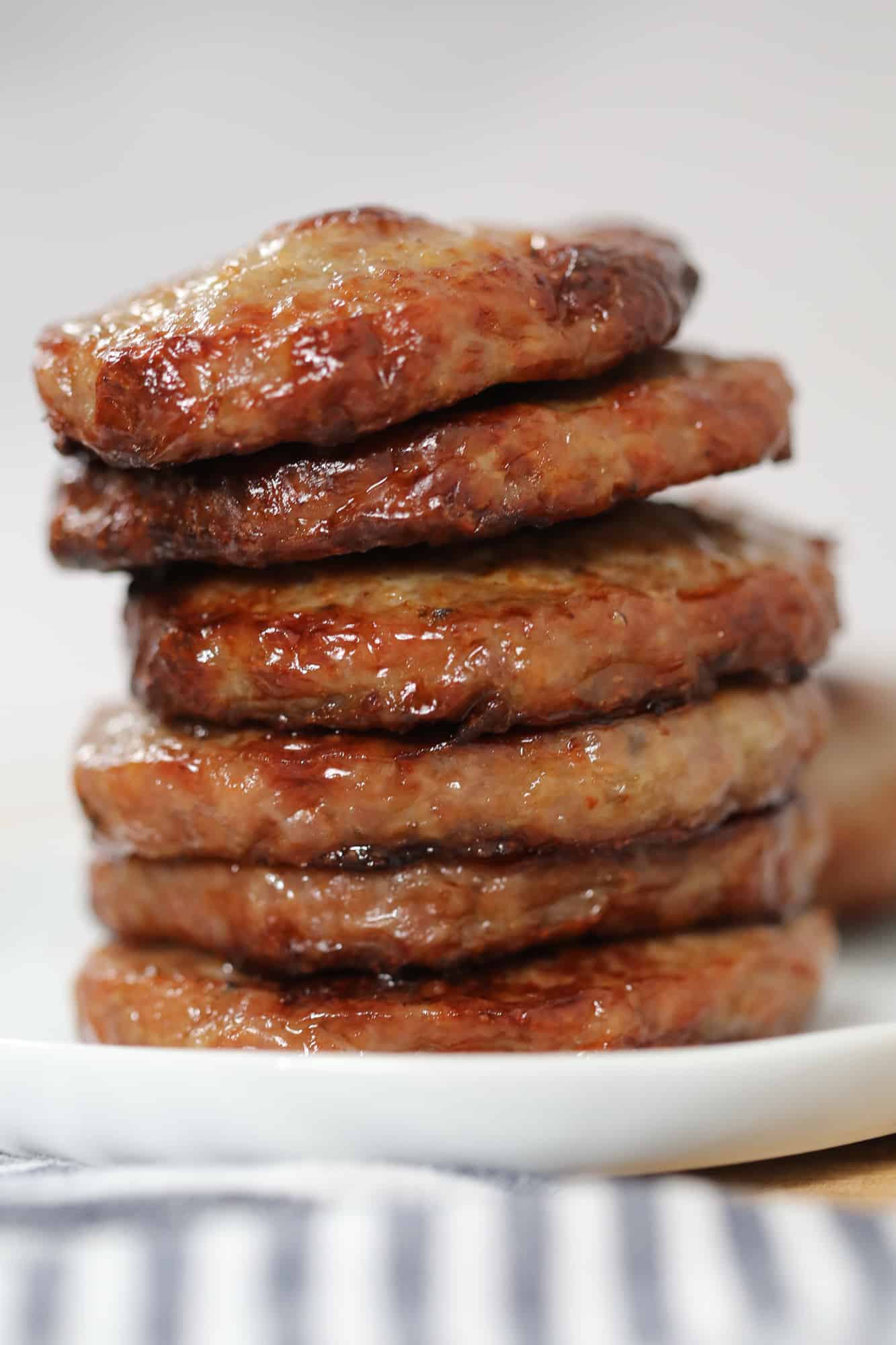 sausage patties in air fryer stacked on a white plate