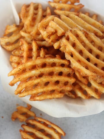 alexia air fryer frozen waffle fries in a white basket ready to eat