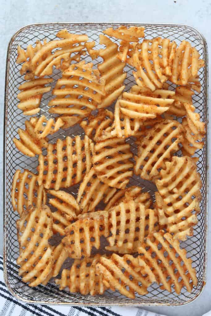 the frozen air fryer waffle fries laying in a basket before cooking