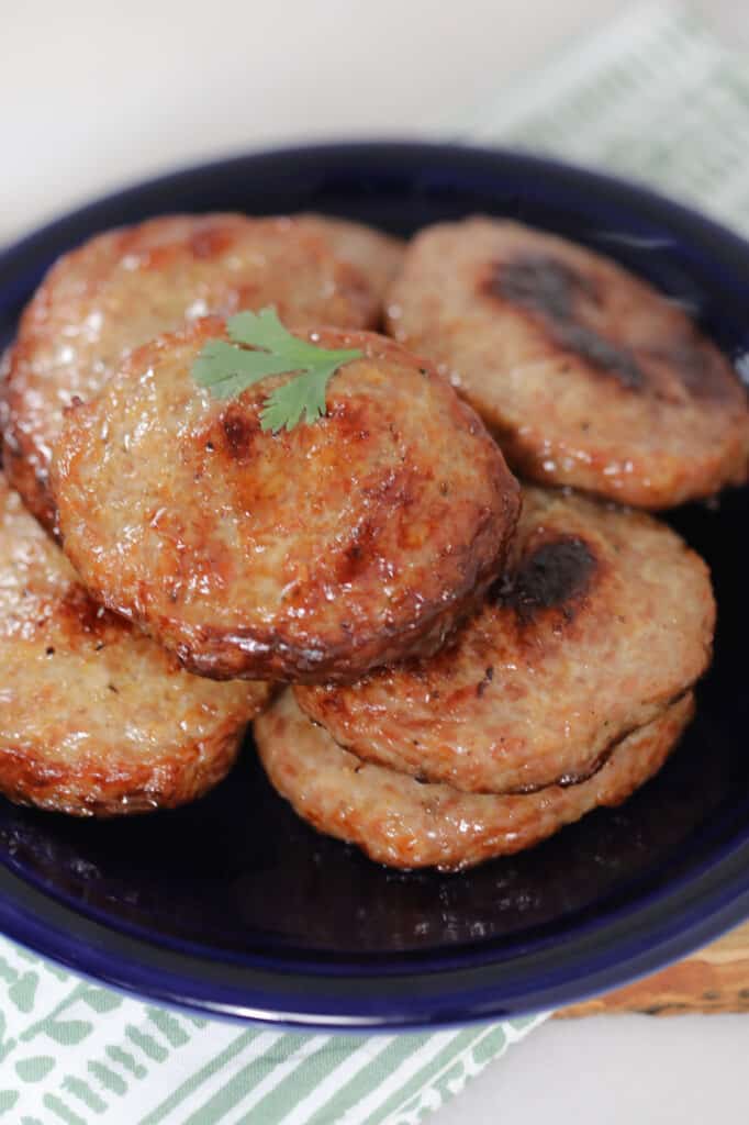 baking sausage patties in the oven after cooking stacked on a black plate