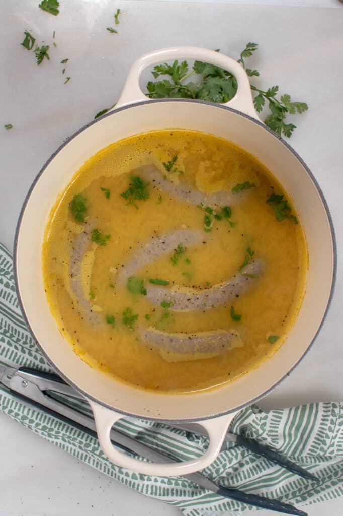 boiled italian sausage in a dutch oven with chicken broth and herbs