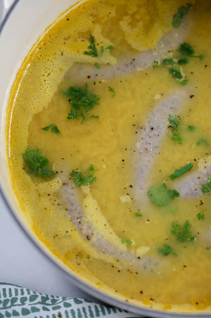 boiled sausage in a pot with chicken broth before cooking