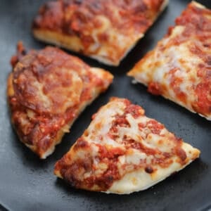 frozen pizza in air fryer cut into 4 on a black plate