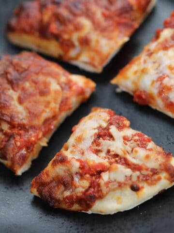 frozen pizza in air fryer cut into 4 on a black plate