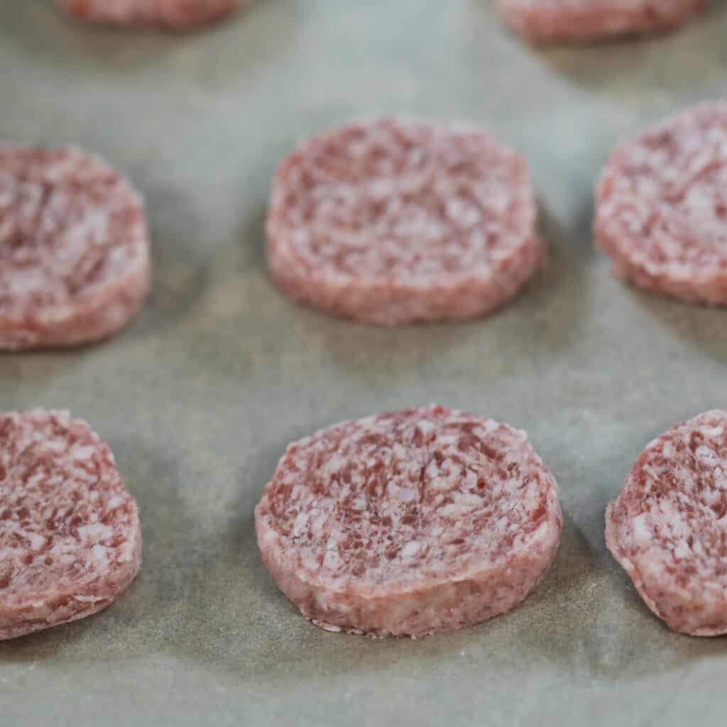 how to cook sausage patties in the oven starts with placing raw sausage on a baking sheet