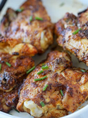 air fryer chicken thighs bone in skin on recipe on a white plate after air frying