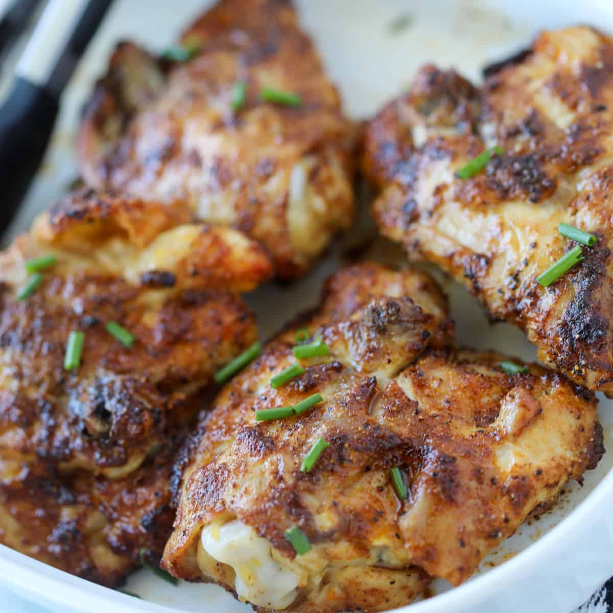 air fryer chicken thighs bone in skin on recipe on a white plate after air frying