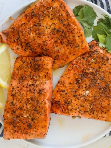 air fryer frozen salmon on a white plate with lemon