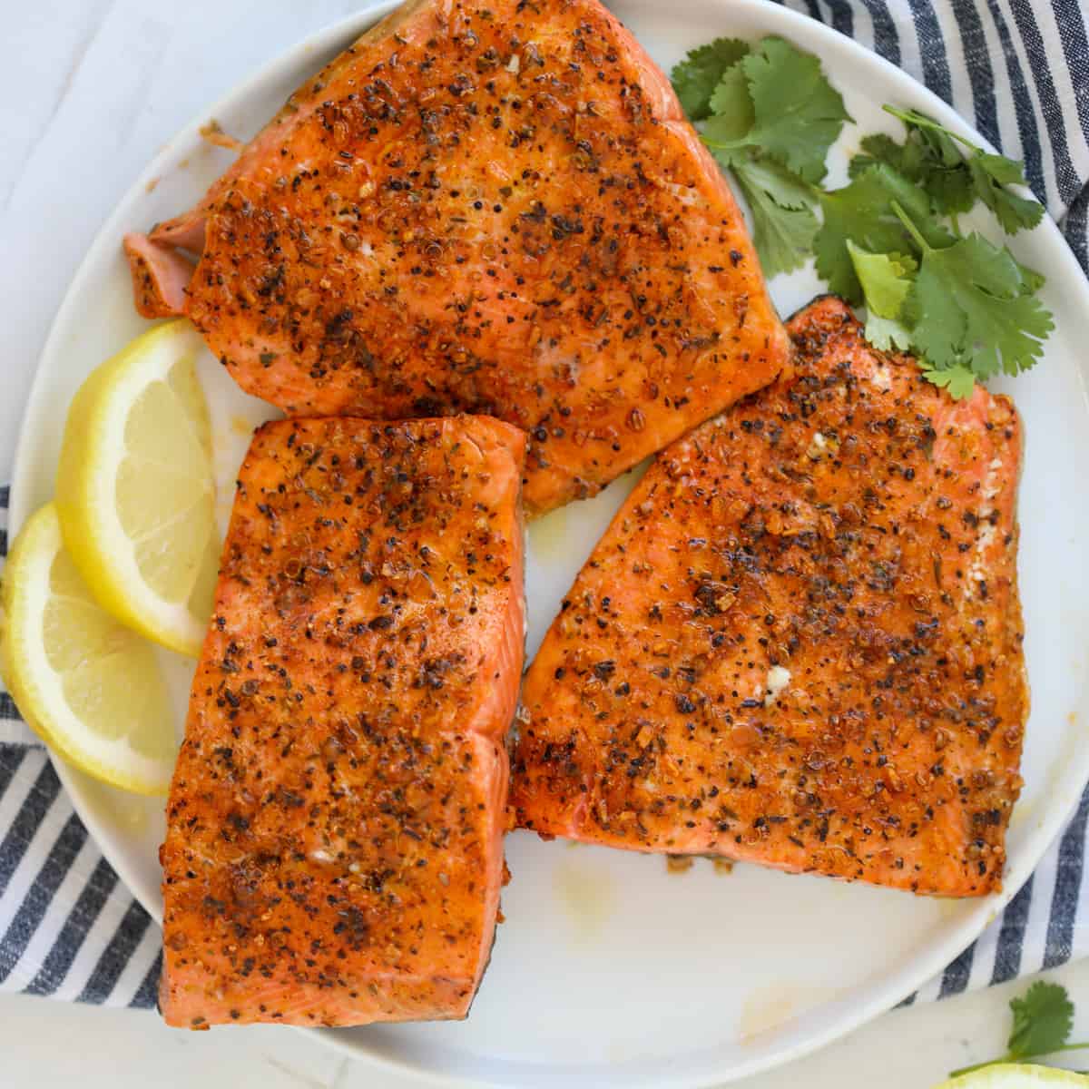 air fryer frozen salmon on a white plate with lemon