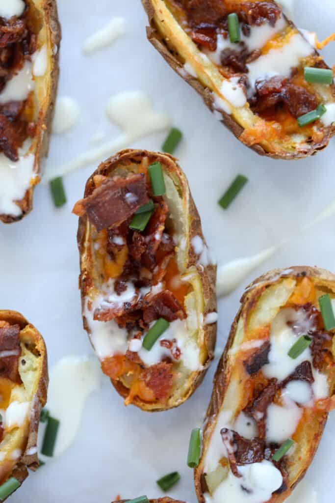air fryer potato skins drizzled with Ranch on parchment paper