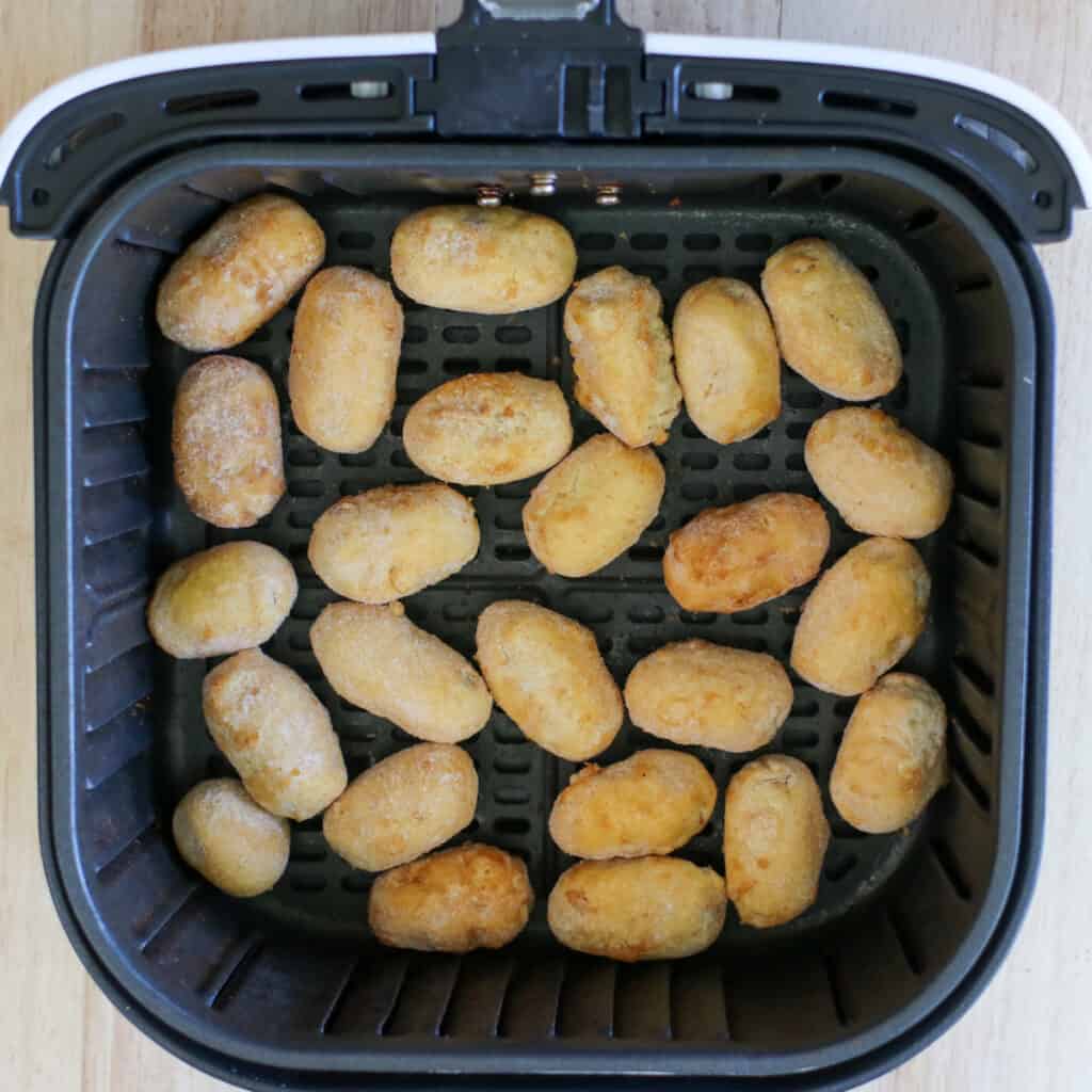 mini corn dogs in air fryer basket before cooking