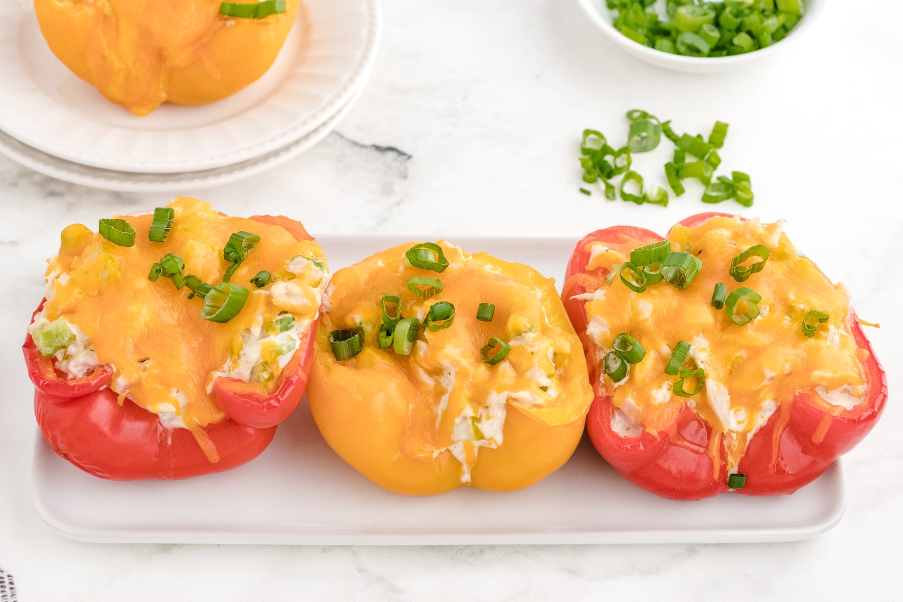 a row of tuna melt stuffed peppers on a platter with melted cheese on top