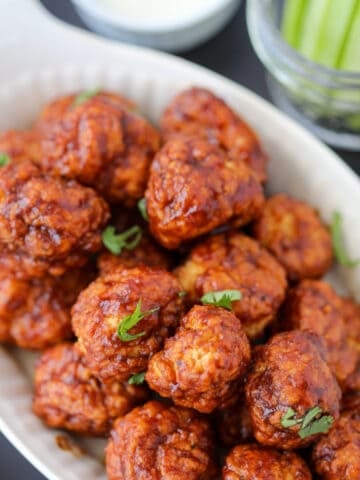 air fryer boneless chicken wings chicken bites from frozen with buffalo hot sauce in a white dish