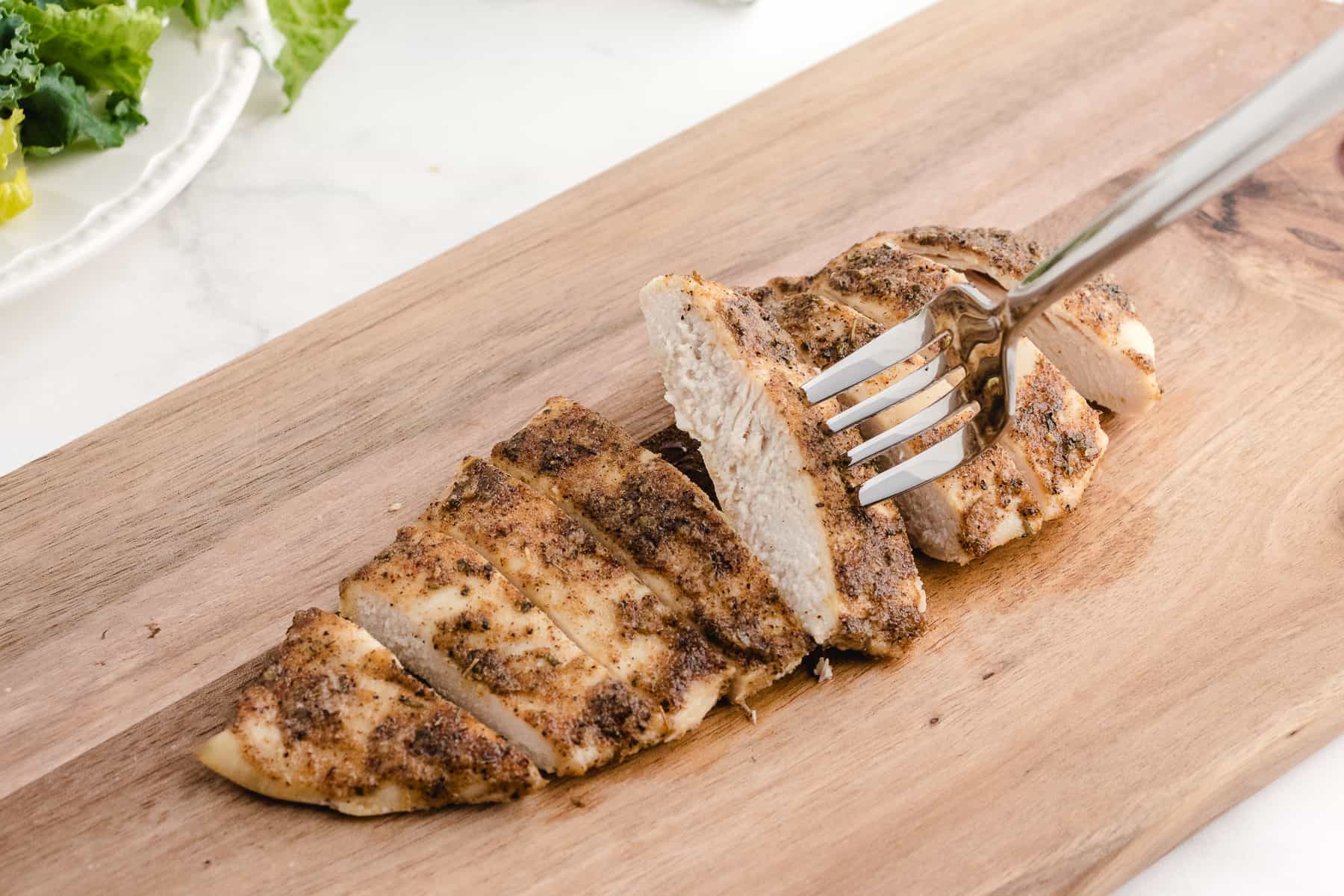 baked thin sliced chicken breast on a cutting board