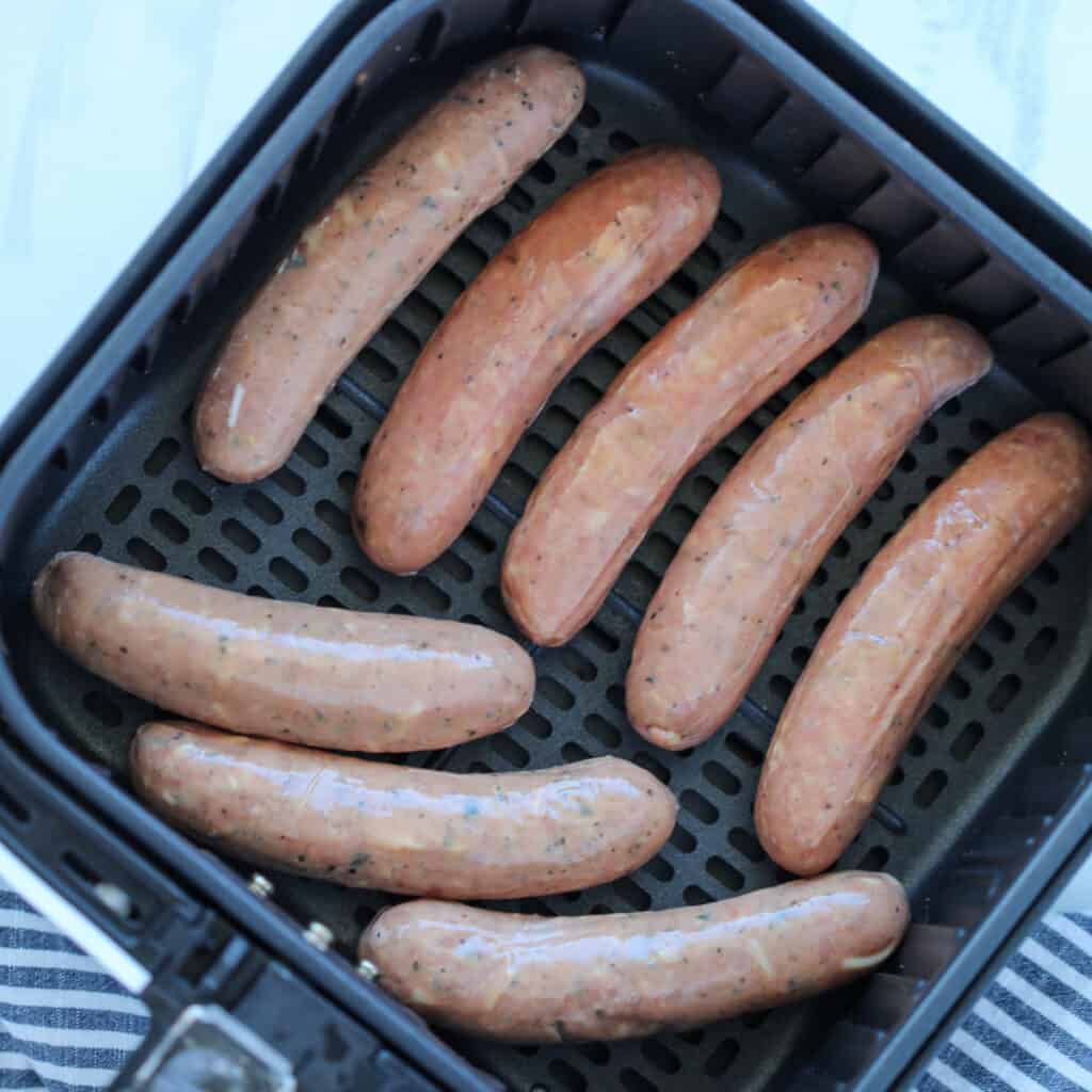 the chicken sausage air fryer recipe starts with spacing out the cold sausages in the basket