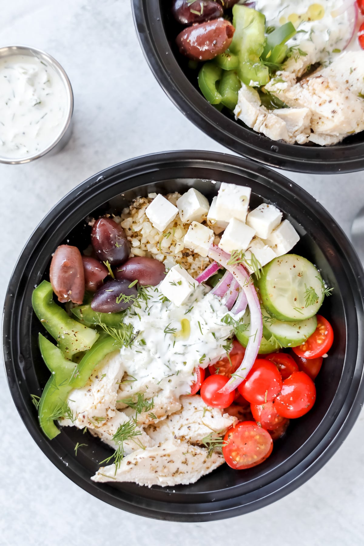 greek salad meal prep bowls assembled and ready to eat with roasted chicken tzatziki sauce and greek salad