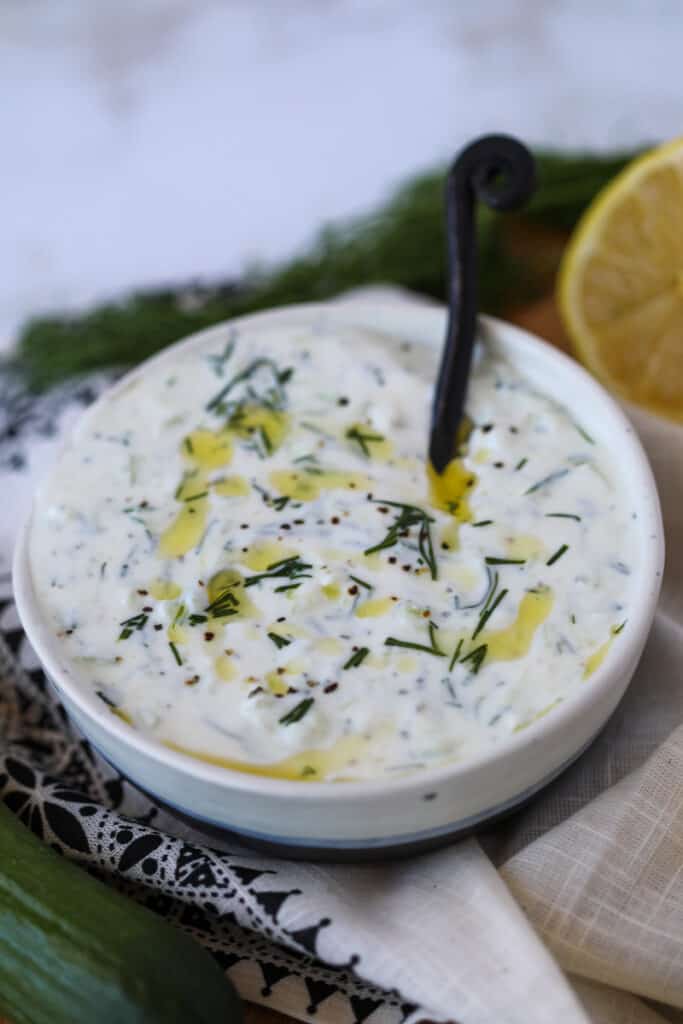 healthy tzatziki sauce in a white bowl with a dill garnish