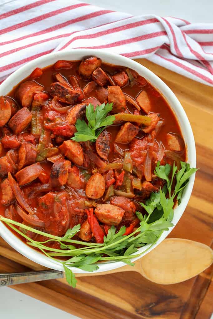 crockpot kielbasa peppers and onions in a white serving dish